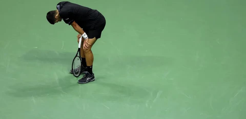 Jugador de tenis agachado sosteniendo una raqueta