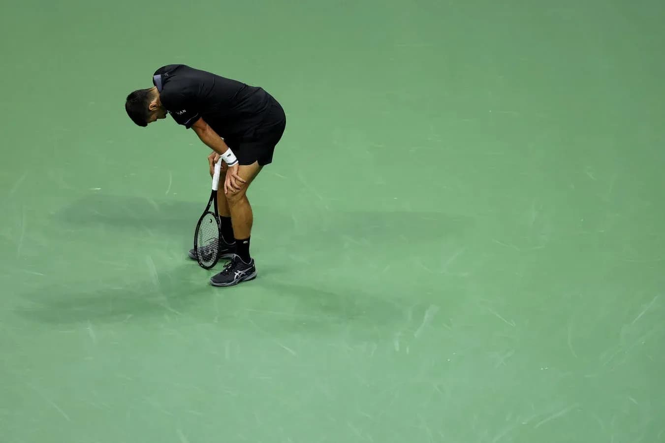 Jugador de tenis agachado sosteniendo una raqueta