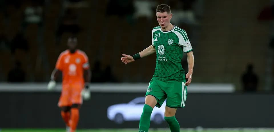 Jugador con uniforme verde controlando el balón en el campo
