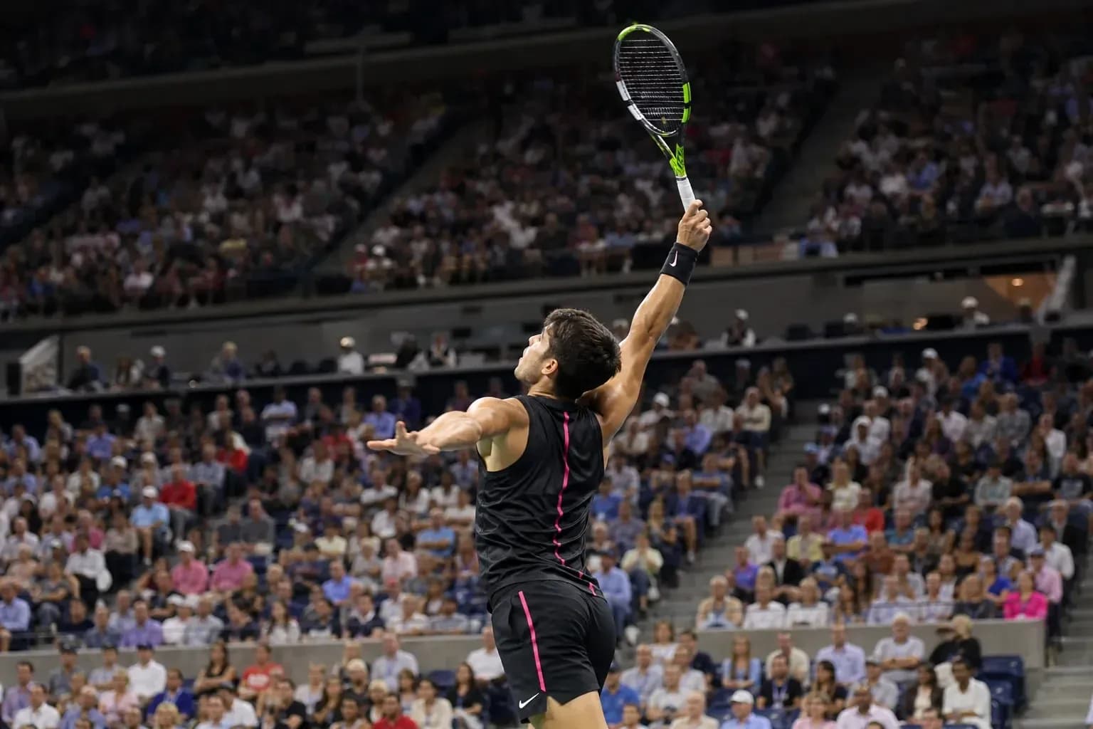 Jugador de tenis sacando en partido con público