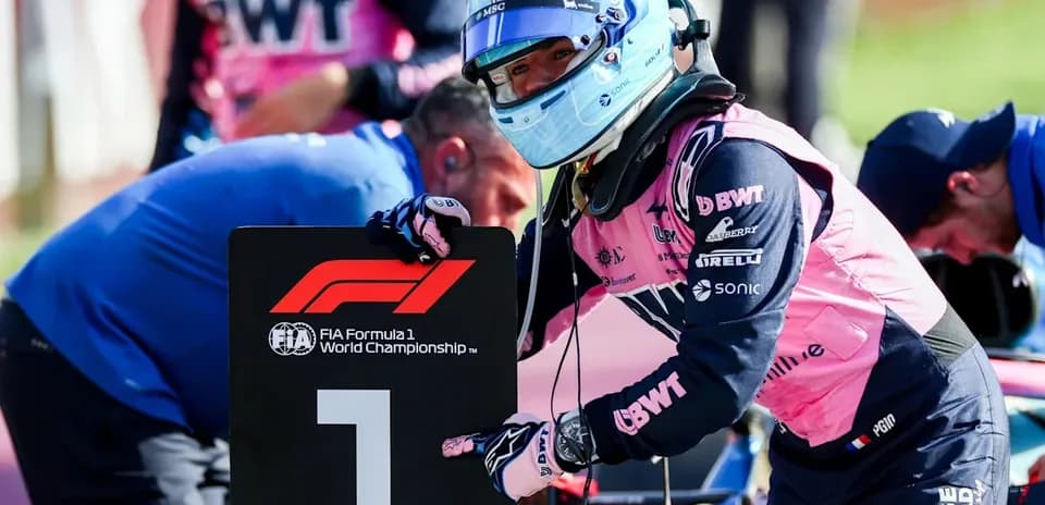 Piloto sosteniendo cartel de F1 en el paddock