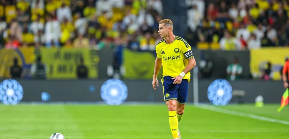Jugador con camiseta amarilla corriendo tras balón en campo