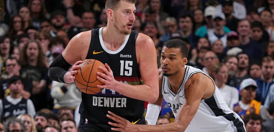Jugador de Denver driblando con balón, defensa cerca