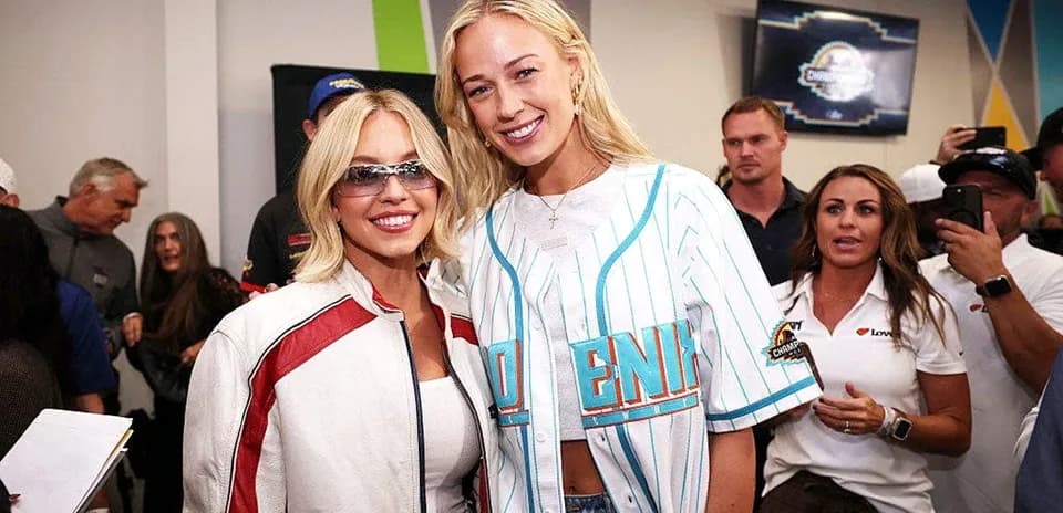 Dos mujeres posando en un evento con público