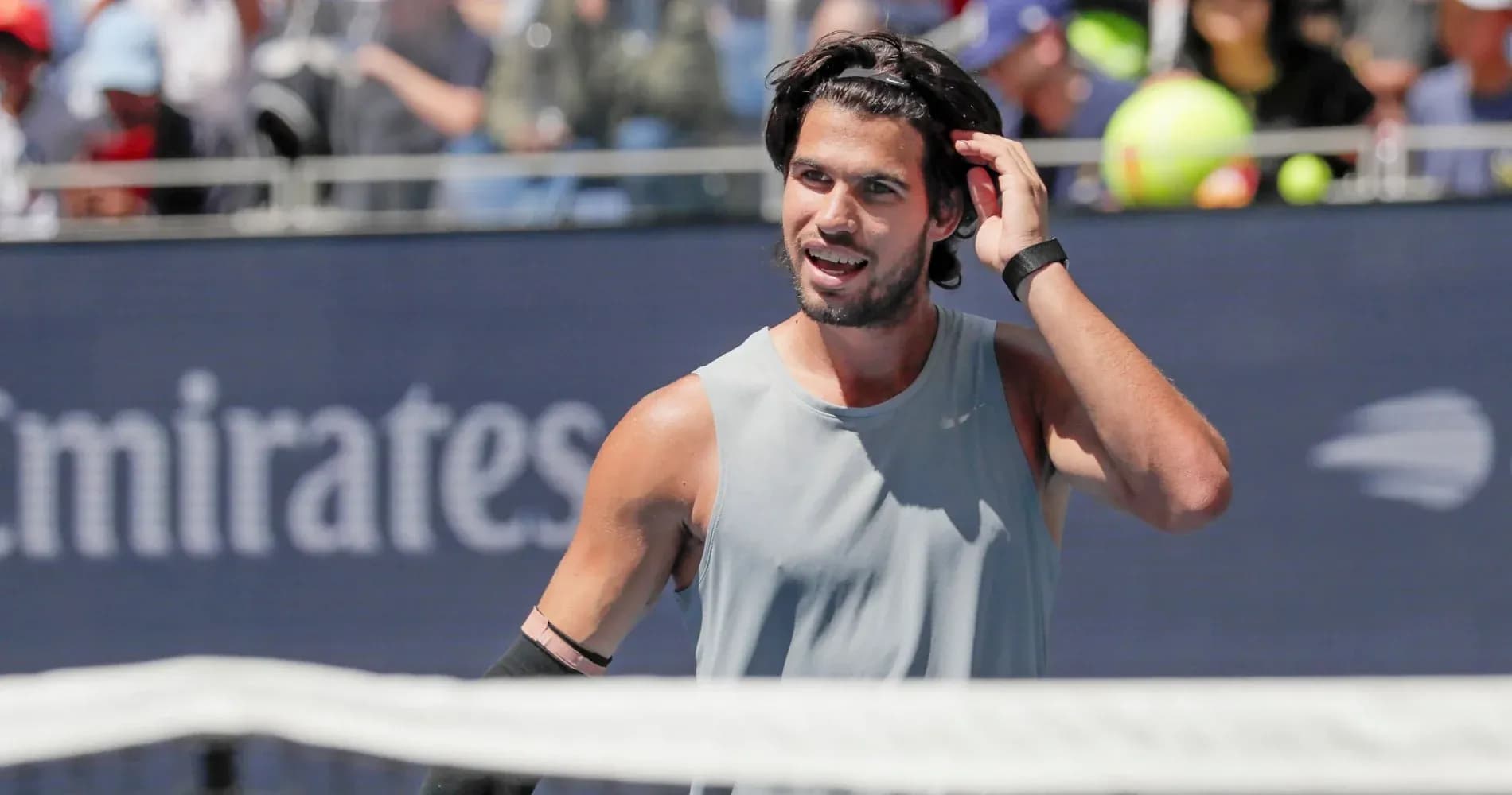 Jugador de tenis ajustando su cabello durante el partido