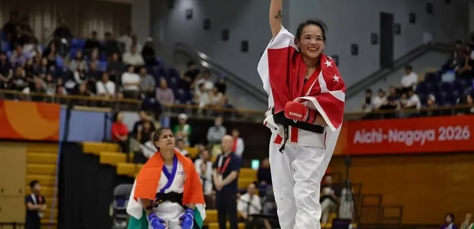 Competitor celebrating victory with raised fist in dojo