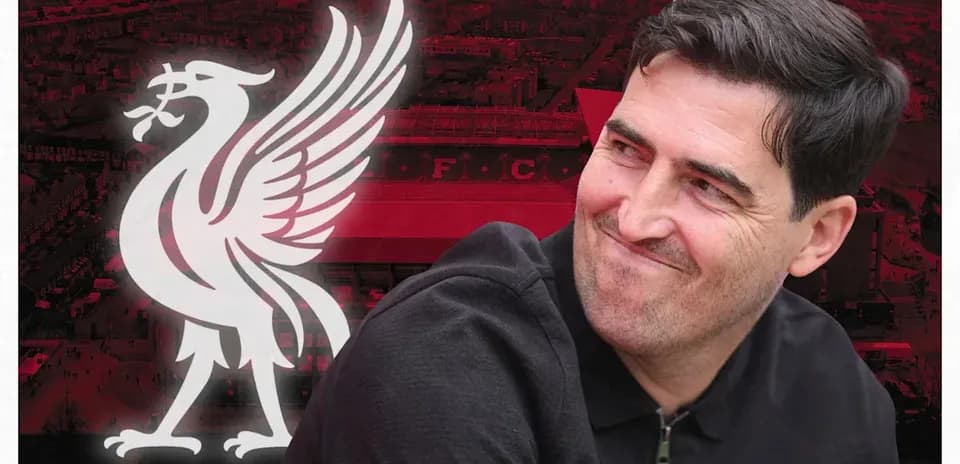 Entrenador sonriendo frente al logo de Liverpool