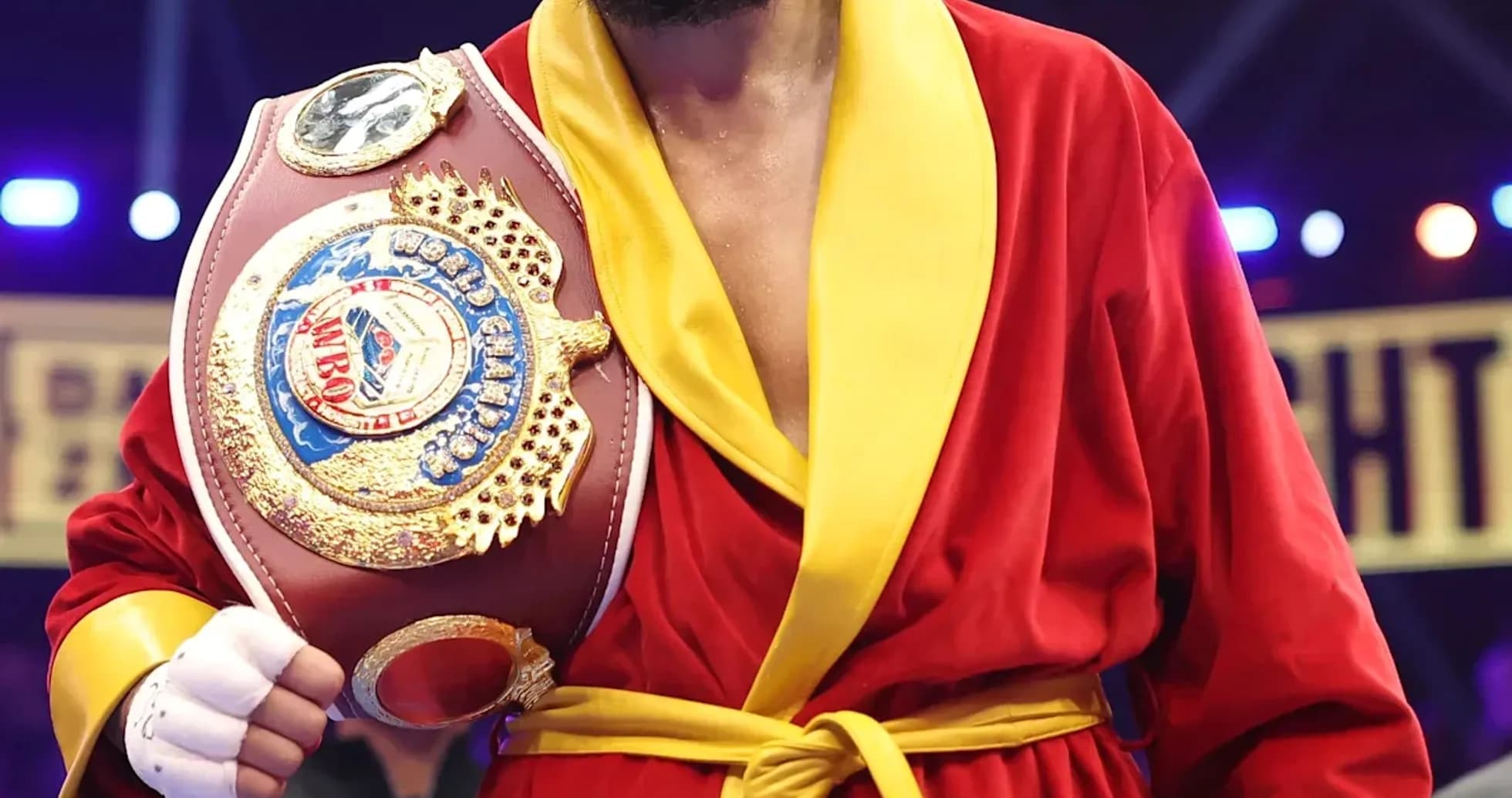 Boxeador sosteniendo cinturón de campeón en el ring