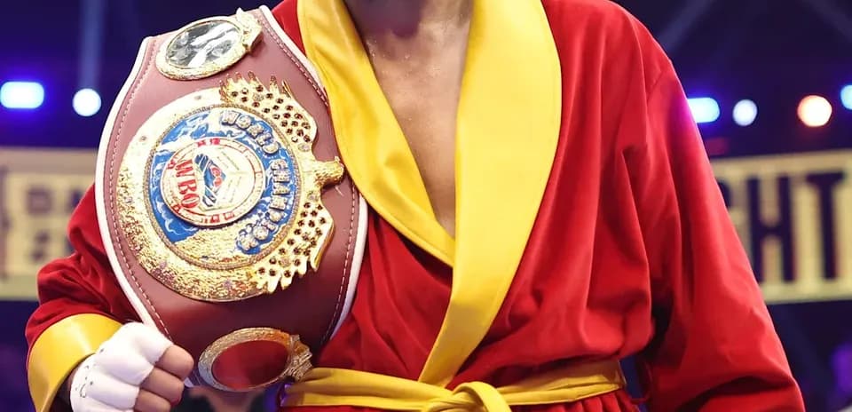 Boxeador sosteniendo cinturón de campeón en el ring