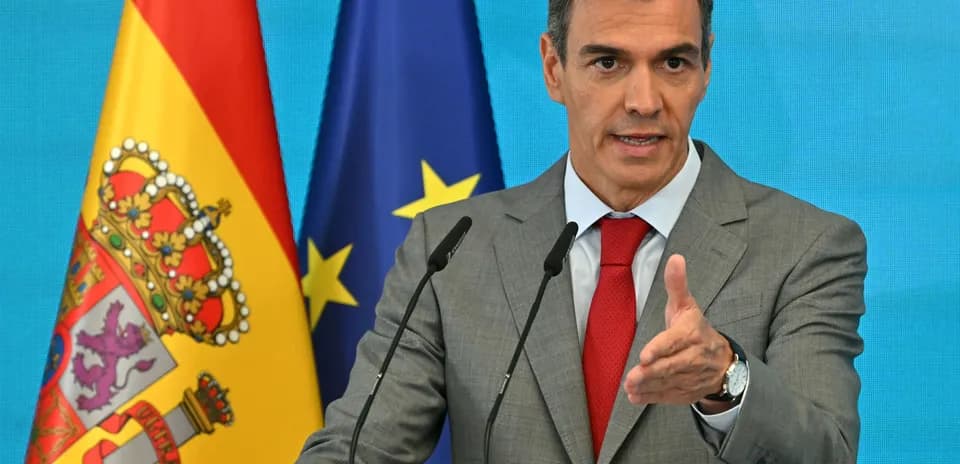 Hombre hablando en un podio con banderas detrás