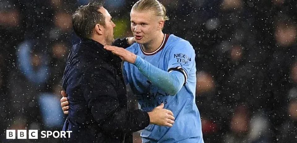 Jugador de Manchester City hablando con entrenador en lluvia