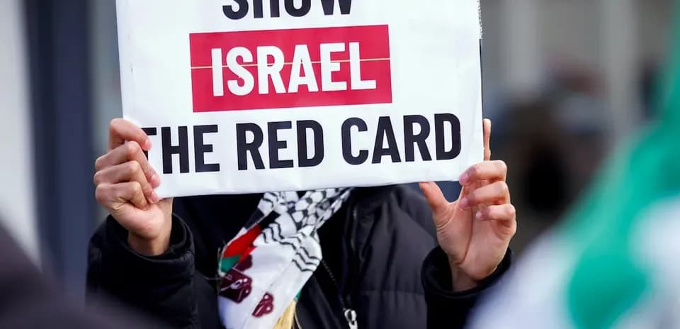 Persona sosteniendo un cartel que dice 'SHOW ISRAEL THE RED CARD'