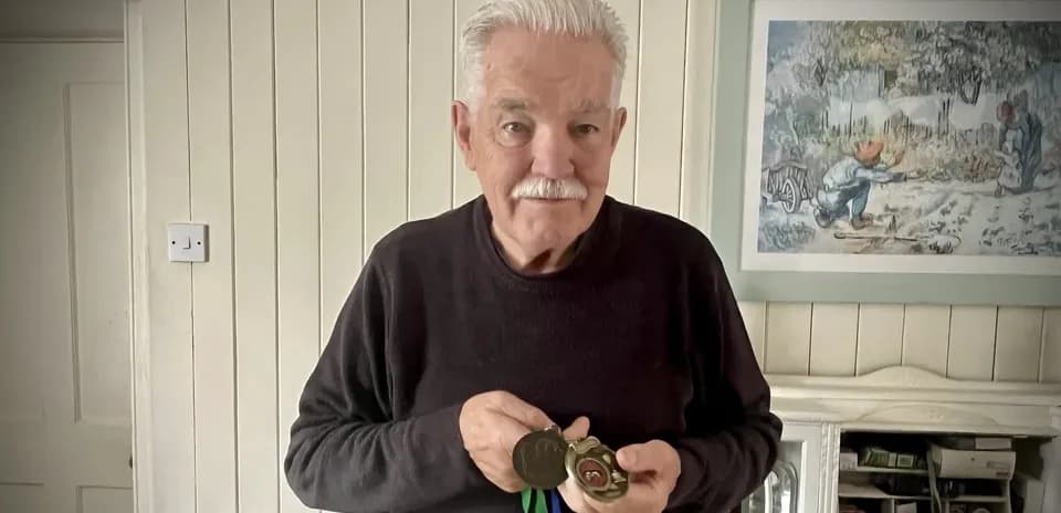Hombre mayor sosteniendo medallas en casa