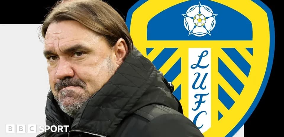 Entrenador con chaqueta negra frente al escudo de Leeds United