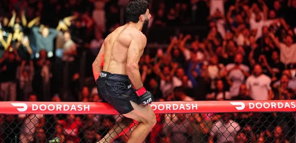 Luchador celebrando sobre la jaula con público animado