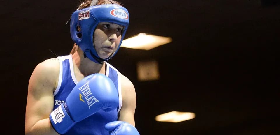 Boxeadora en acción con guantes azules y casco