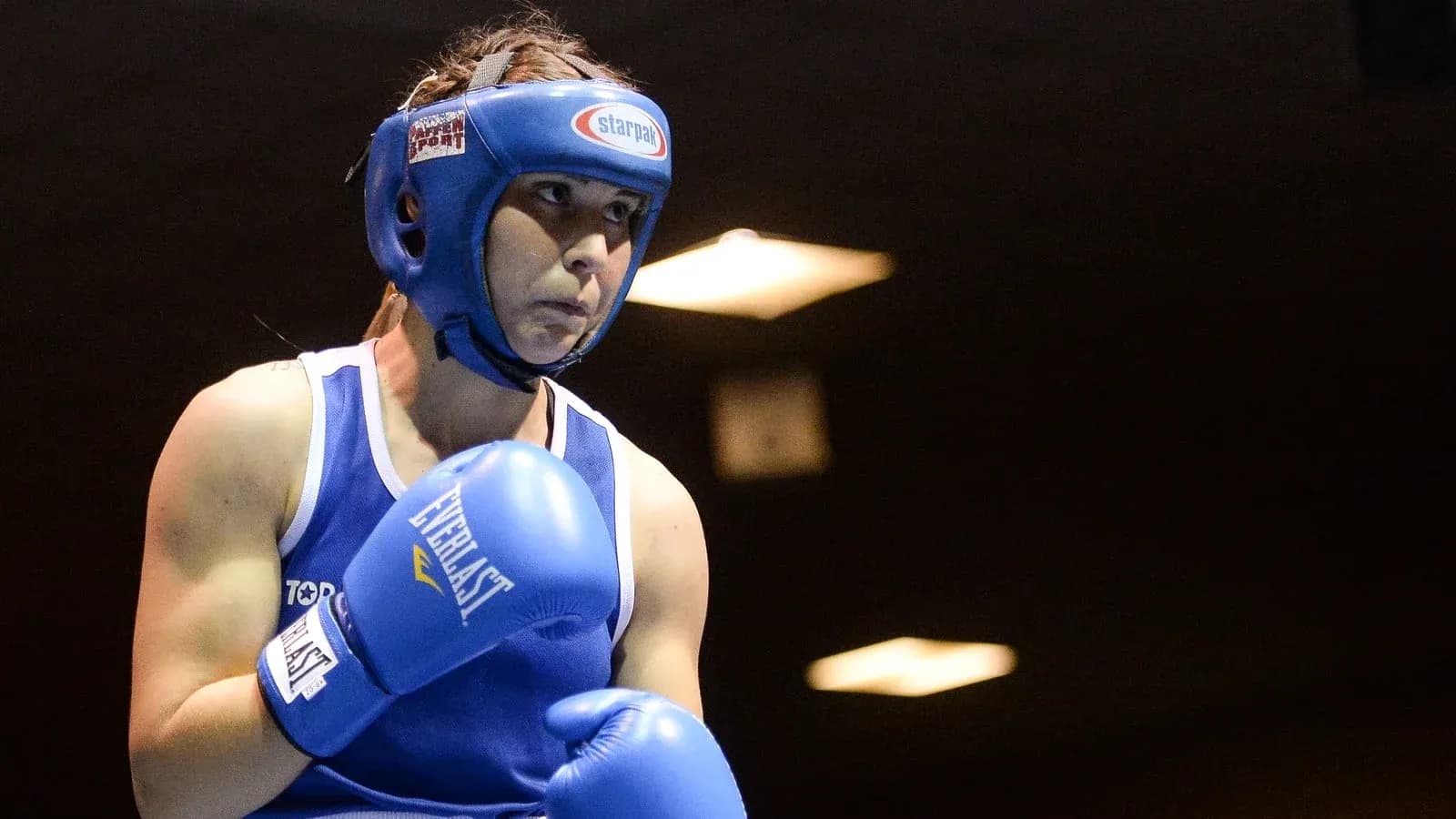 Boxeadora en acción con guantes azules y casco