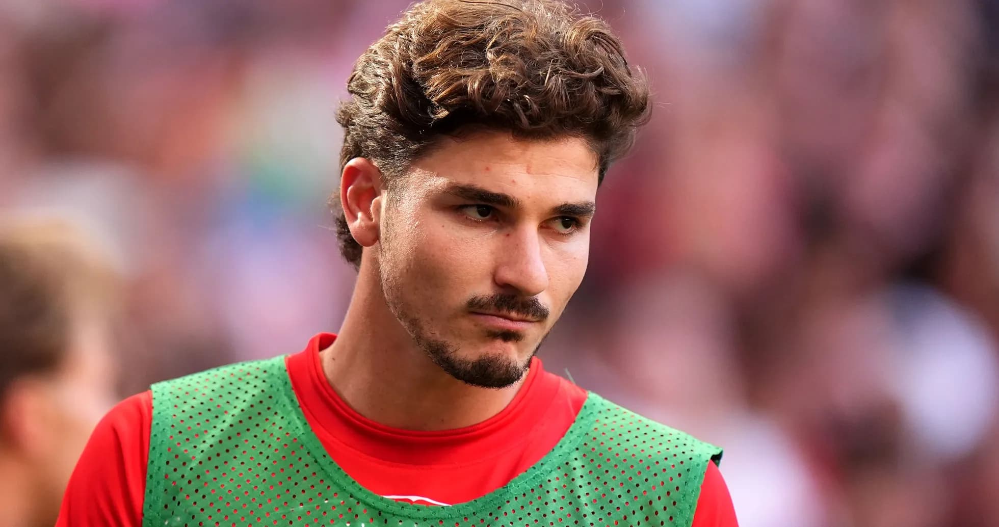 Jugador con camiseta roja y chaleco verde en el campo