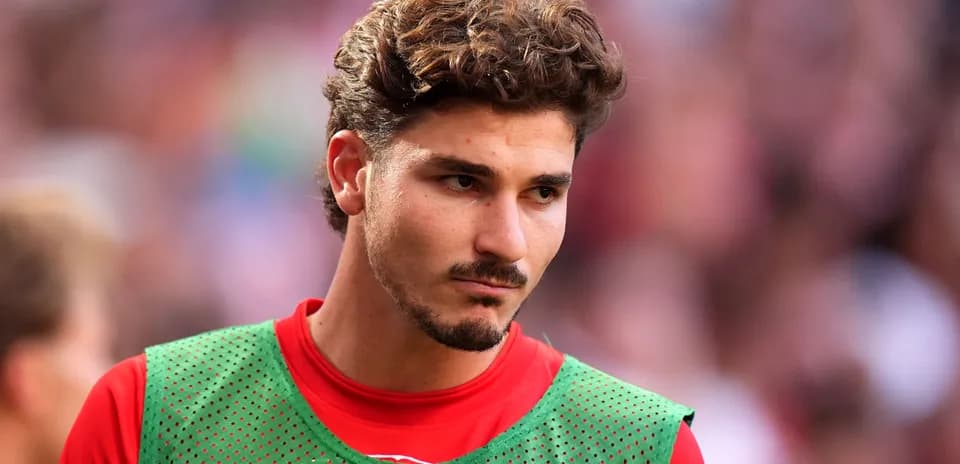Jugador con camiseta roja y chaleco verde en el campo
