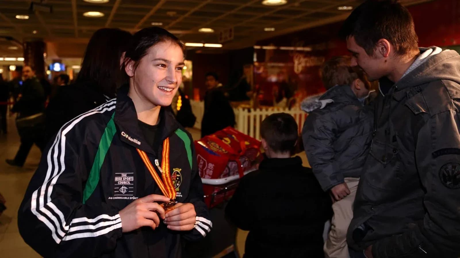 Atleta con medalla sonriendo en un aeropuerto