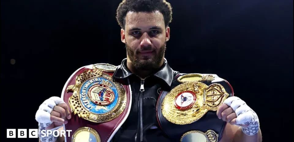 Boxeador sosteniendo cinturones de campeonato en el ring