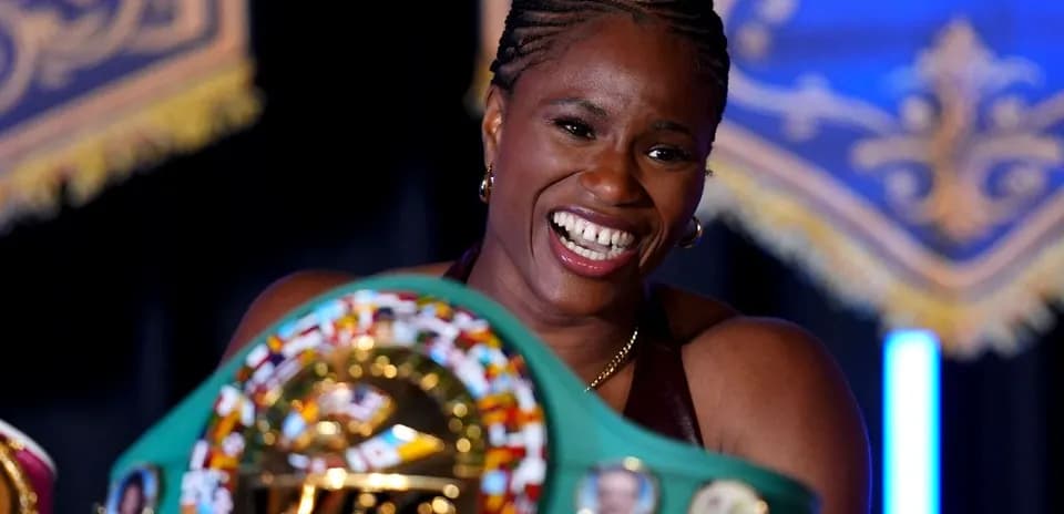 Boxeadora sosteniendo su cinturón de campeón sonriente