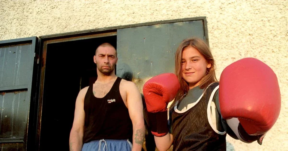 Niña con guantes de boxeo y entrenador en puerta