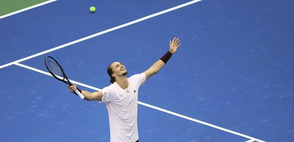 Jugador de tenis celebrando en la cancha azul