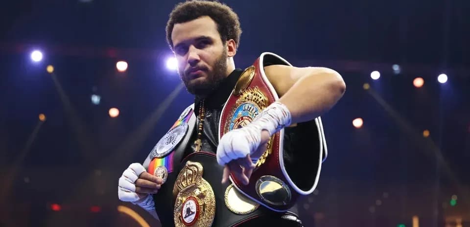 Boxeador posando con cinturones de campeón