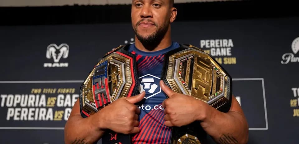 Luchador sosteniendo cinturones de campeón en conferencia