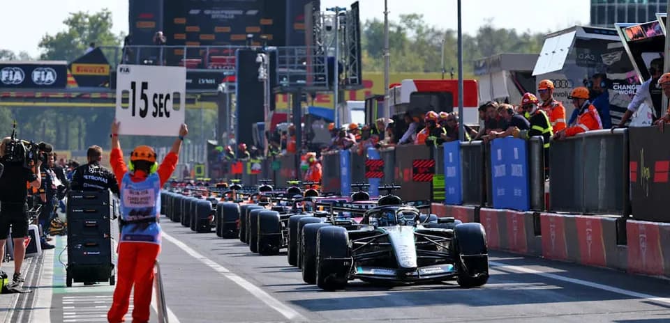 Pilotos de F1 en la parrilla con señal de penalización
