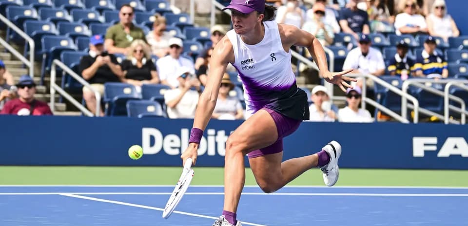 Jugadora de tenis alcanzando una pelota en la cancha