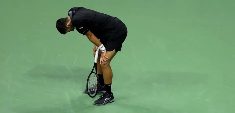 Jugador de tenis agachado en la cancha