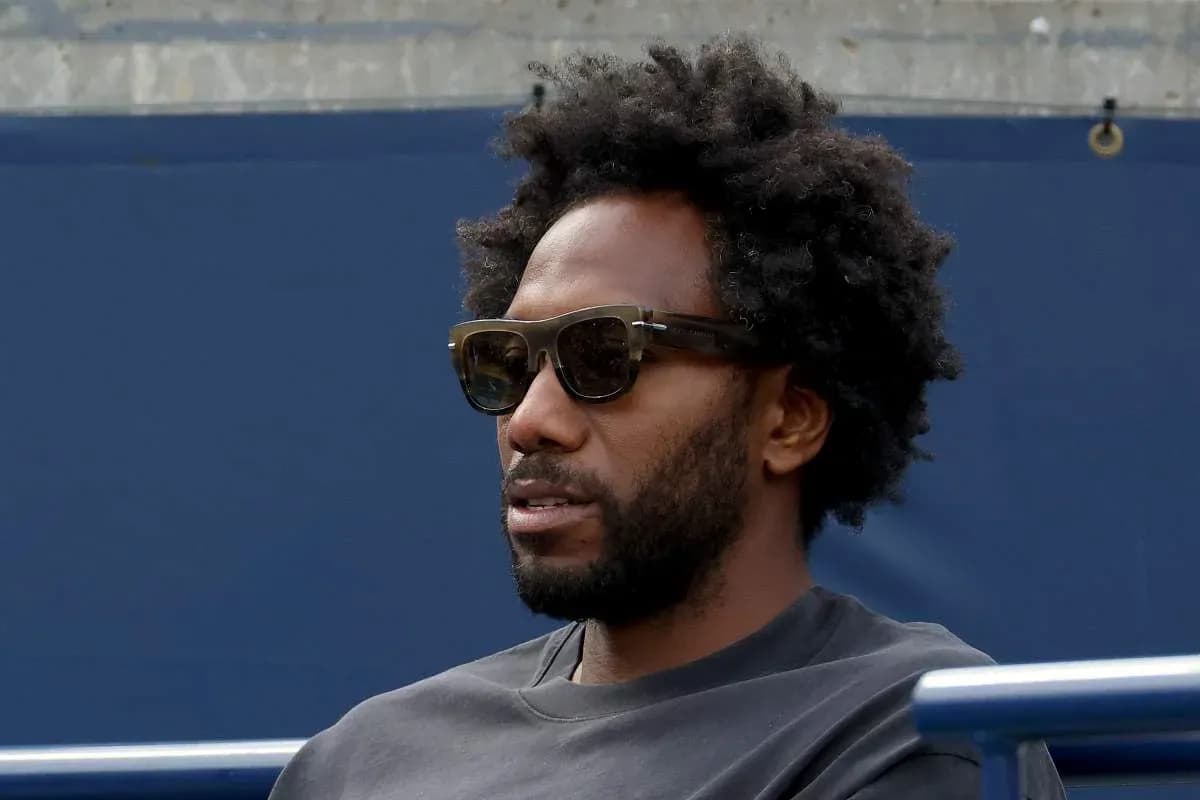 Hombre con gafas oscuras sentado en la tribuna