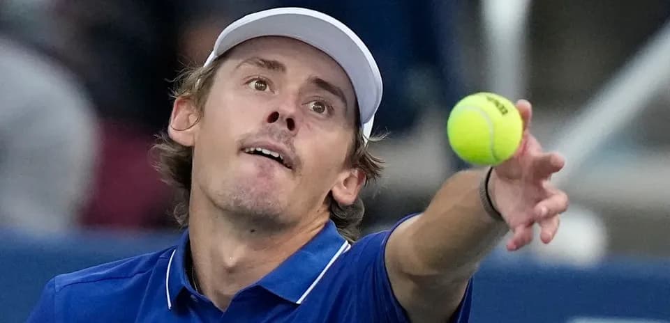 Jugador lanzando una pelota de tenis en saque