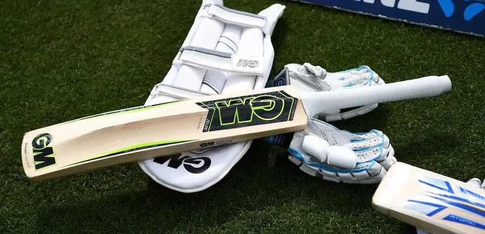 Equipo de cricket incluyendo bate y guantes en césped