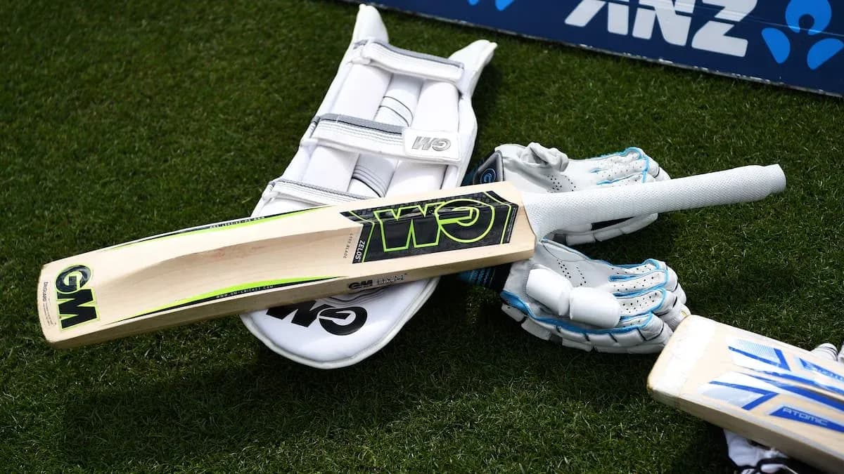 Equipo de cricket incluyendo bate y guantes en césped