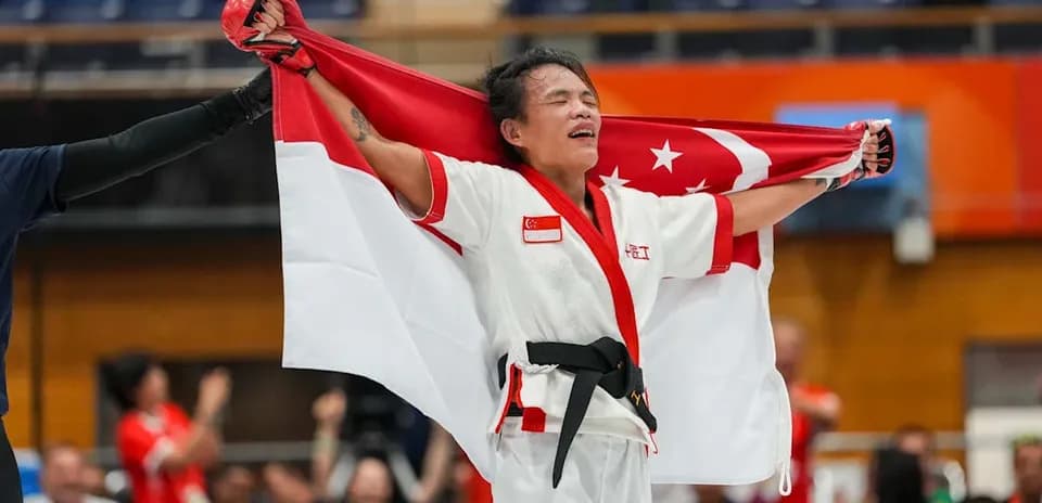 Atleta sosteniendo la bandera de Singapur tras victoria