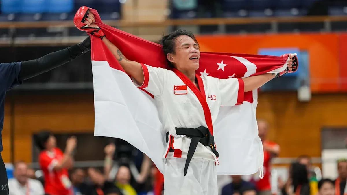 Atleta sosteniendo la bandera de Singapur tras victoria