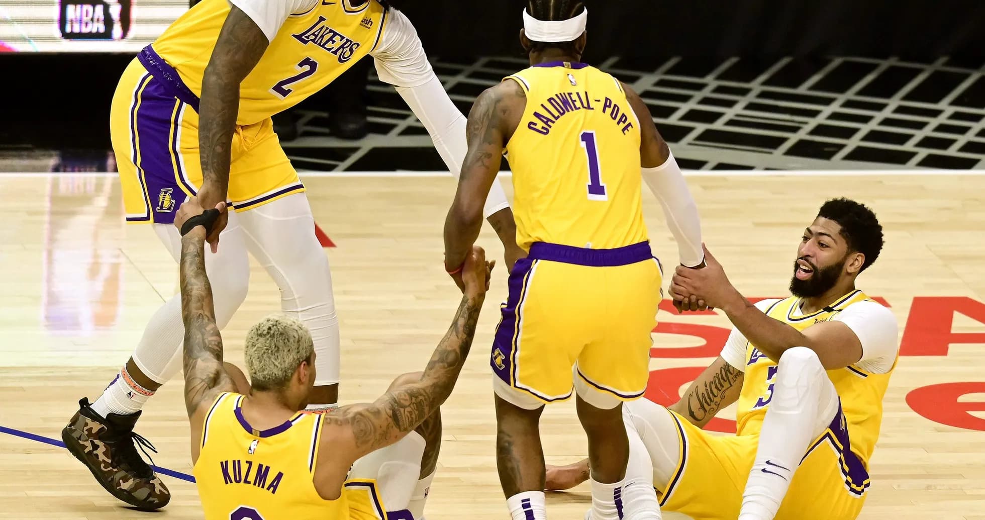 Jugadores de los Lakers ayudan a Kuzma y Davis en el suelo