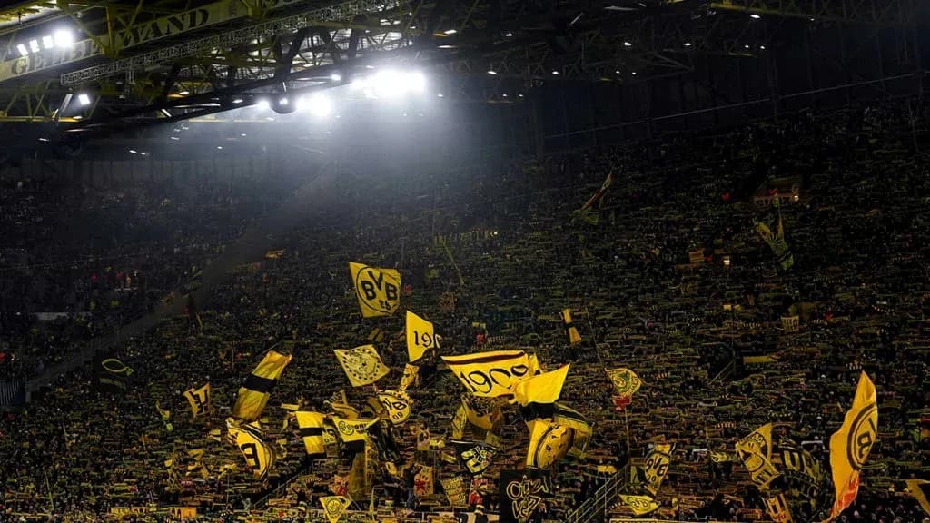 Aficionados de Borussia Dortmund con banderas en estadio Aficionados de Borussia Dortmund con banderas en estadio