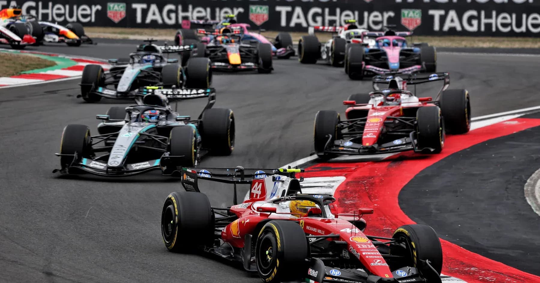 Varios coches de Fórmula 1 compitiendo en una curva Varios coches de Fórmula 1 compitiendo en una curva