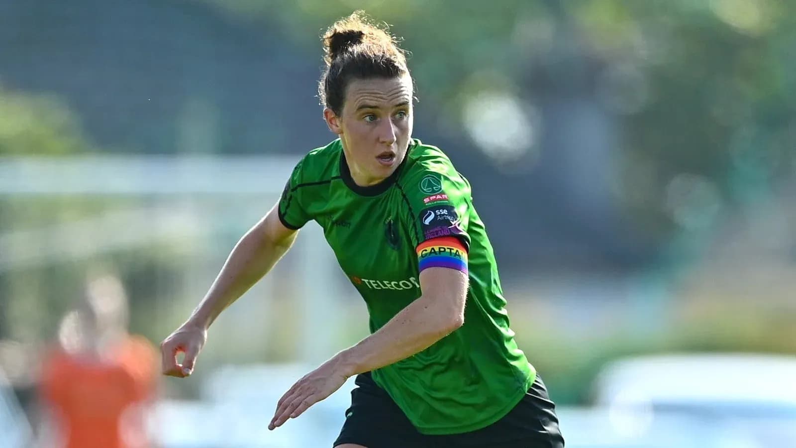 Jugadora en acción con camiseta verde y cinta de capitán Jugadora en acción con camiseta verde y cinta de capitán