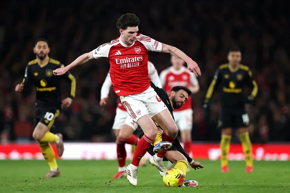 Jugador del Arsenal driblando mientras es tackleado Jugador del Arsenal driblando mientras es tackleado