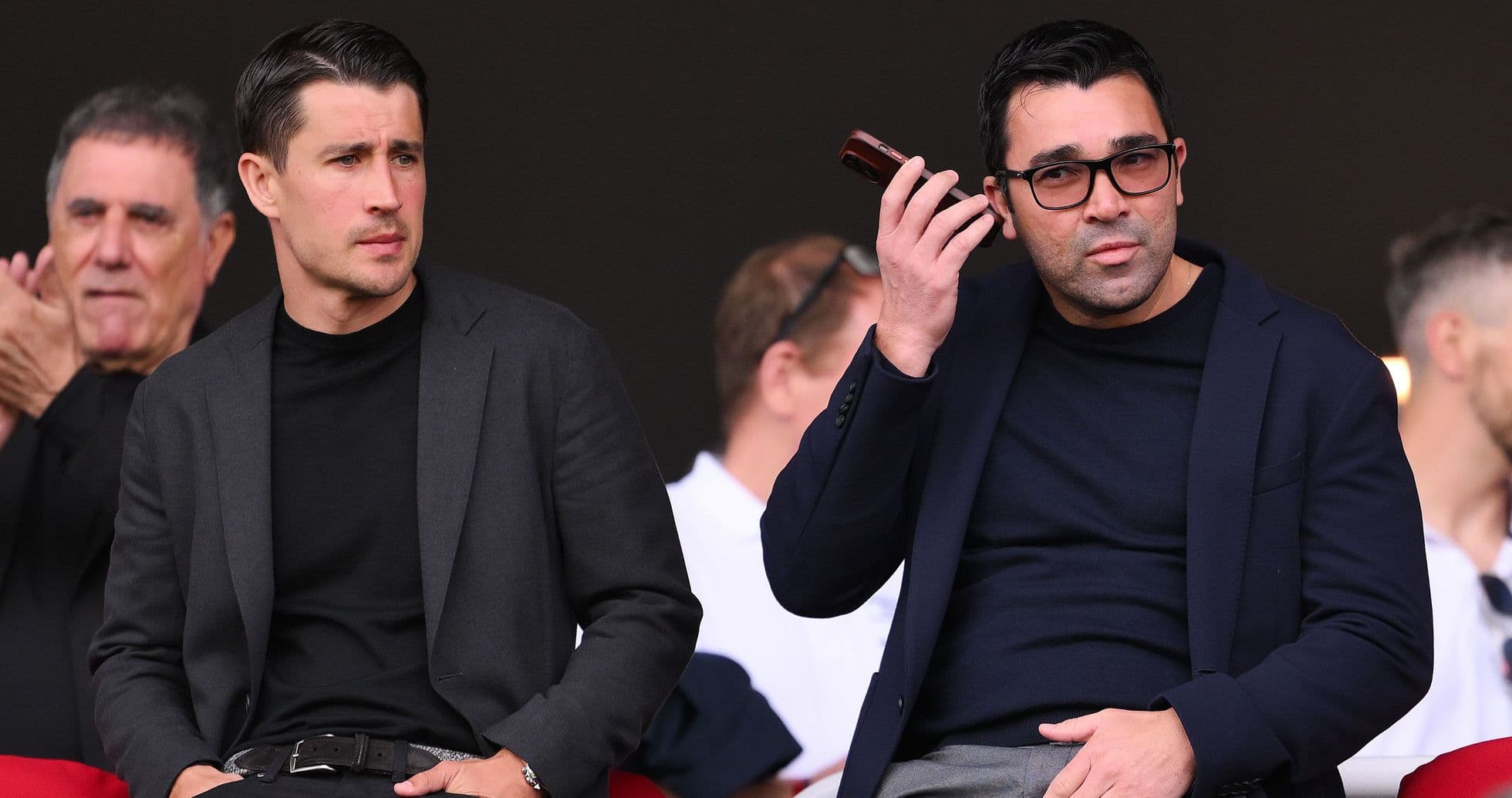 Dos hombres en un palco durante un evento deportivo Dos hombres en un palco durante un evento deportivo