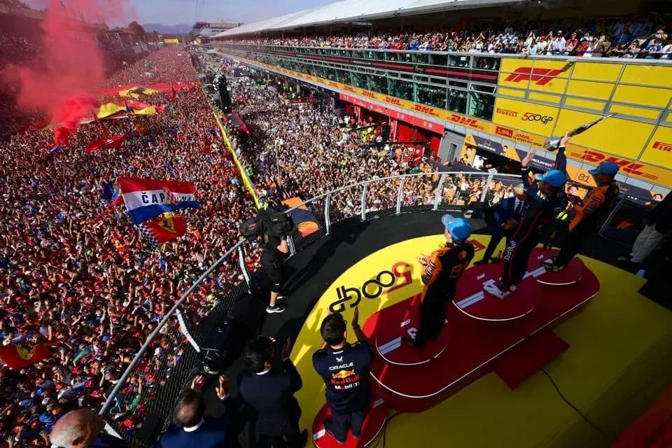 Podio de premiación con pilotos y multitud celebrando Podio de premiación con pilotos y multitud celebrando