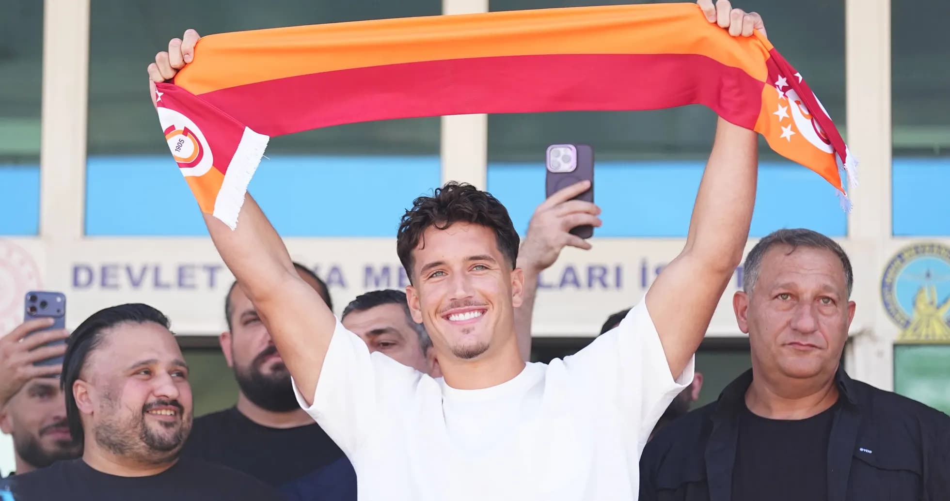 Jugador sosteniendo una bufanda de Galatasaray en evento Jugador sosteniendo una bufanda de Galatasaray en evento